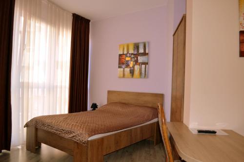 1 dormitorio con cama, escritorio y ventana en Apart Center 22/7 en Plovdiv