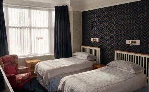 a hotel room with two beds and a chair at Abinger Guest House in Leicester