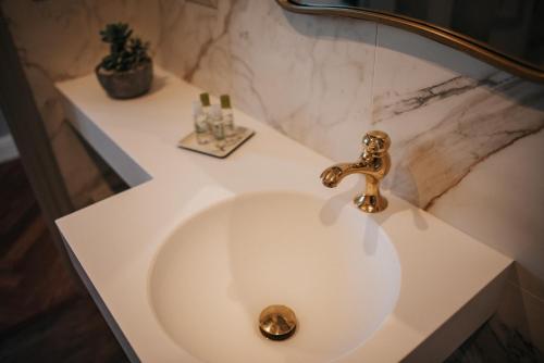a white bathroom sink with a gold faucet at 1930 Boutique Hotel in Arzúa