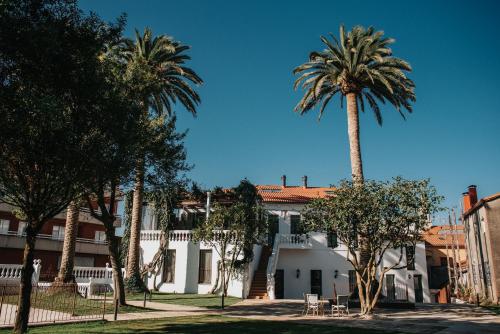 a group of palm trees in front of a building at 1930 Boutique Hotel in Arzúa