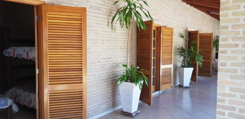 a patio with two potted plants on a brick wall at Chacara Recanto dos Passaros 01 in Olímpia