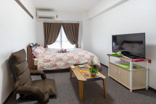 1 dormitorio con 1 cama, TV y silla en Cozyhouse 310 free wifi a rented electric bicycle en Kyoto