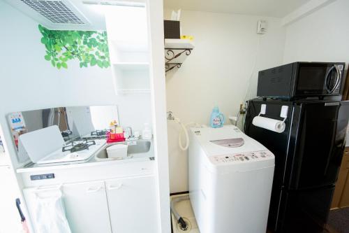 a small kitchen with a sink and a black refrigerator at Cozyhouse 310 free wifi a rented electric bicycle in Kyoto