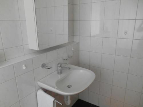 ein weißes Badezimmer mit einem Waschbecken und einem Spiegel in der Unterkunft Vazerol in Lenzerheide
