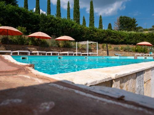 a large swimming pool with umbrellas and chairs at Hotel Villa San Giorgio in Poggibonsi