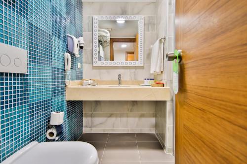 W łazience znajduje się umywalka, toaleta i lustro. w obiekcie Crystal Club World of Colours w mieście Belek