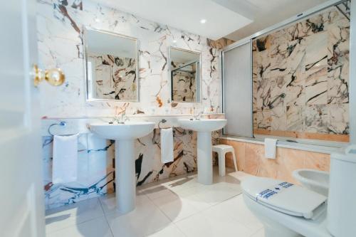 uma casa de banho com 2 lavatórios e um WC em Hollywood Mirage - Excel Hotels & Resorts em Los Cristianos