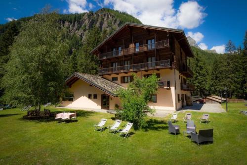 a large building with a bunch of chairs in the yard at Alpine Forest Hotel in Champoluc
