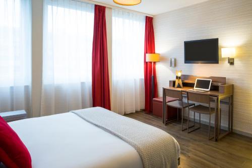 a hotel room with a bed and a desk at Aparthotel Adagio Basel City in Basel