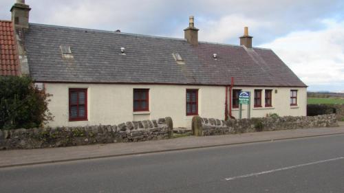 a white house with a gray roof on a street at Osnaburgh B&B in Cupar