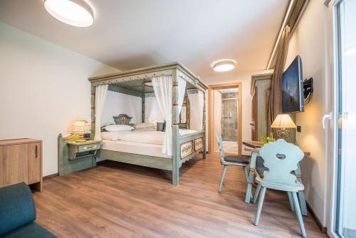 a bedroom with a canopy bed and a desk at Vitaurina Royal Hotel in Molini di Tures