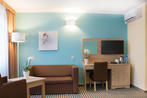 ブィドゴシュチュにあるHotel Ameliaのソファとテーブルとテレビのある部屋