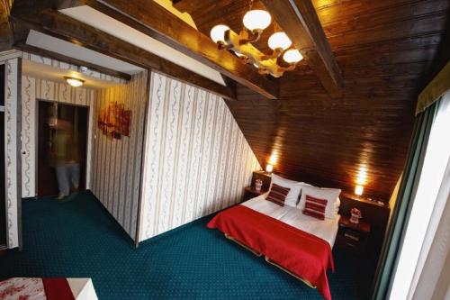 um quarto com uma cama com um cobertor vermelho em Noclegi I Restauracja Zodiak em Gliwice