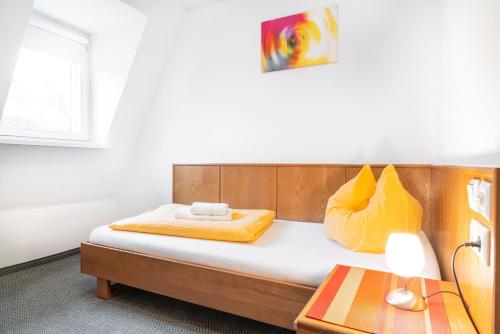a bedroom with a bed with yellow pillows and a table at Brauhaus Gummersbach GmbH in Gummersbach