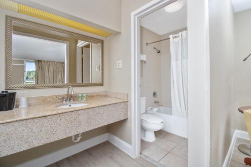 een badkamer met een wastafel, een toilet en een spiegel bij Stayable Lakeland in Lakeland