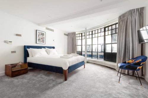 a bedroom with a large bed and a blue chair at Hausd - Piccadilly Circus in London
