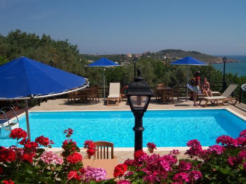 a blue swimming pool with a blue umbrella and flowers at Efta Anemi - Benovias in Karfas