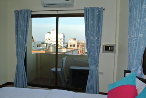 a bedroom with a window with a view of a city at Baan Taweesuk Guest House in Hua Hin