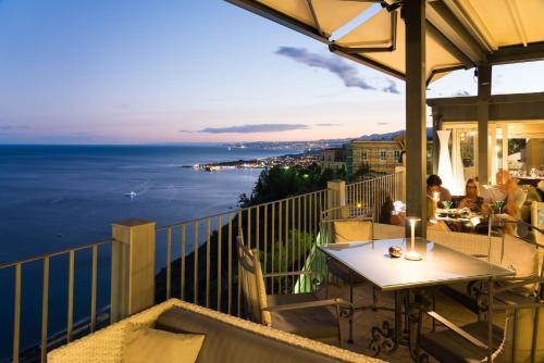 a balcony with a table and a view of the ocean at Hotel Metropole Taormina in Taormina