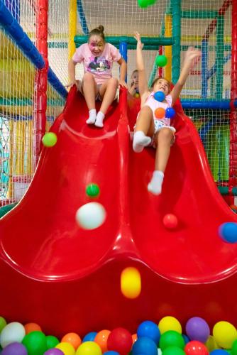 two girls sitting on a slide at a playground at Apartamentos Santa Rosa in Costa Teguise