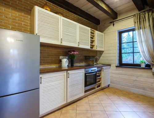 Una cocina con gabinetes blancos y un refrigerador. en 5 stories, en Inkartai