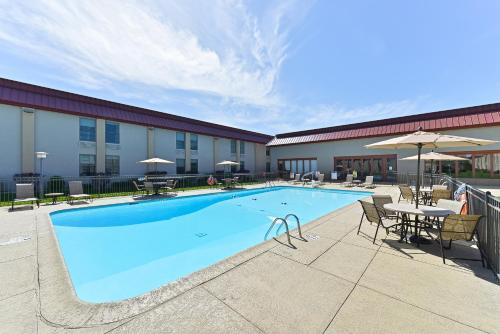 a pool at a hotel with tables and chairs and umbrellas at Holiday Inn Cody - Convention Center by IHG in Cody