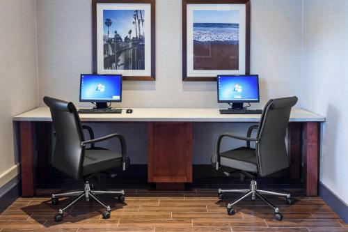 two computer monitors sitting on a desk with two chairs at Holiday Inn Express & Suites Carpinteria by IHG in Carpinteria