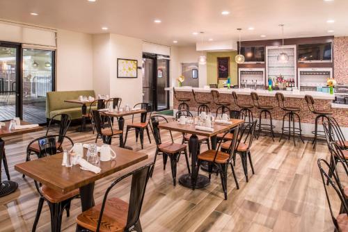 a restaurant with tables and chairs and a bar at Holiday Inn and Suites Addison by IHG in Addison
