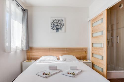 Un dormitorio con una cama blanca con dos platos. en Lyon Confluence - Superbe pied à terre avec parking privé en option en Lyon