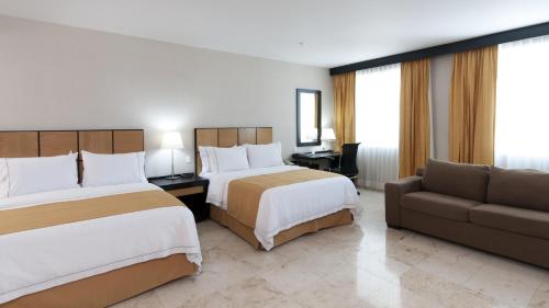 a hotel room with two beds and a couch at Holiday Inn Express Ciudad Del Carmen by IHG in Ciudad del Carmen