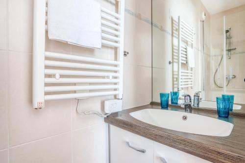 W białej łazience znajduje się umywalka i lustro. w obiekcie Lyon Confluence - Superbe pied à terre avec parking privé en option w mieście Lyon