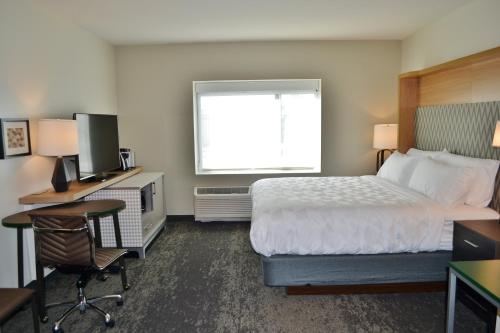 a hotel room with a bed and a desk with a computer at Holiday Inn - Columbus by IHG in Columbus
