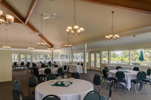 una sala de banquetes con mesas y sillas blancas y ventanas en South Thompson Inn & Conference Centre, en Kamloops
