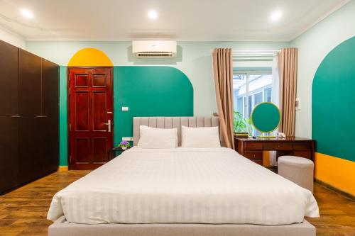 a bedroom with a white bed and a green wall at Ohana House in Hanoi