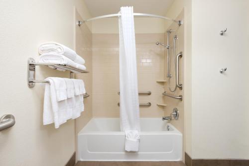 a bathroom with a tub and a shower with towels at Candlewood Suites Columbia Hwy 63 & I-70, an IHG Hotel in Columbia