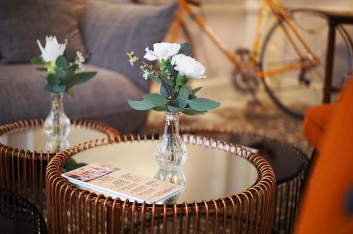 - une table avec un vase en verre et des fleurs dans l'établissement Hôtel du Simplon, à Lyon