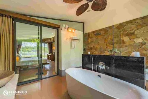un bagno con ampia vasca e parete in pietra di Flamingo Dai Lai Resort - by BAY LUXURY a Yen