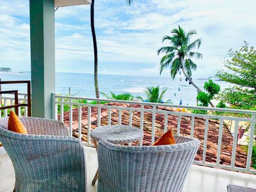 a balcony with chairs and a view of the ocean at Thaproban Beach House in Unawatuna