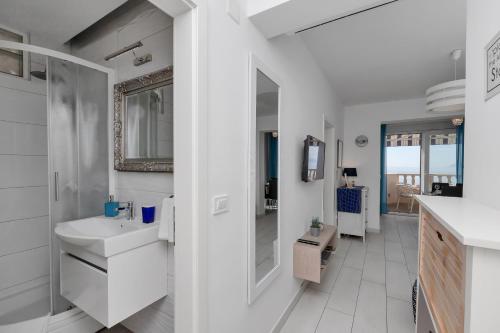 Un baño blanco con lavabo y espejo. en Apartments Villa Joy, en Podgora