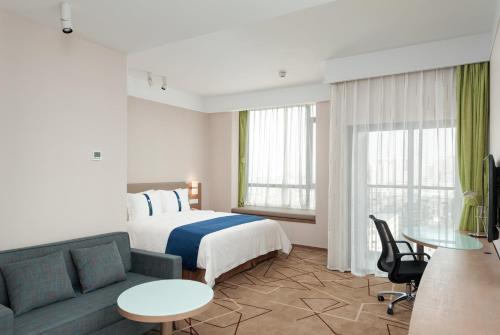 成都市にあるHoliday Inn Express Chengdu West Gate by IHGのベッドとソファのあるホテルの部屋