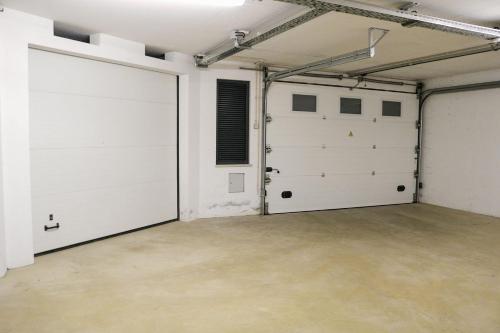 a garage with two white doors and a concrete floor at Ocean Pearl Baleal in Ferrel