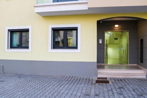 a yellow building with a door and windows at Ocean Pearl Baleal in Ferrel