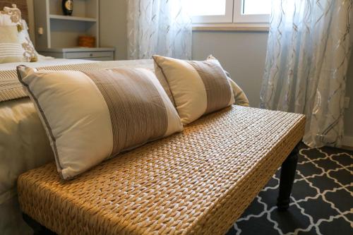 a wicker bench with two pillows on it in a bedroom at Ocean Pearl Baleal in Ferrel