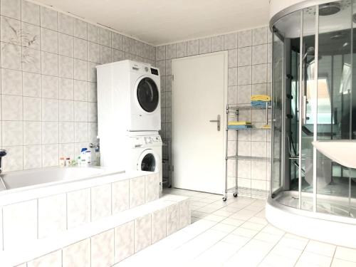 a bathroom with a tub and a washing machine at Ferienwohnung auf denkmalgeschütztem Sturmhof in Grefrath