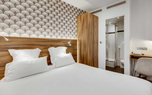 um quarto com uma grande cama branca e uma cabeceira em madeira em Carladez Cambronne em Paris
