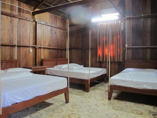 two beds in a room with wooden walls at Homestay Xóm Dừa Nước in Ben Tre