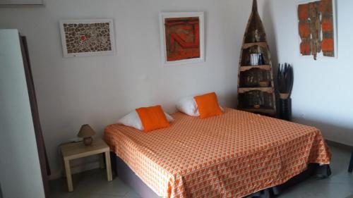 ein Schlafzimmer mit einem Bett mit orangefarbenen Kissen darauf in der Unterkunft STUDIO LE PHARE in Terre-de-Haut