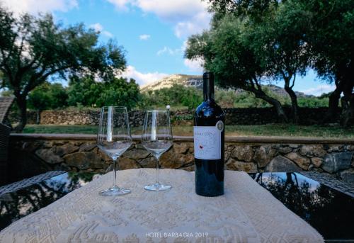 una bottiglia di vino seduta su un tavolo con due bicchieri da vino di Hotel Barbagia a Dorgali