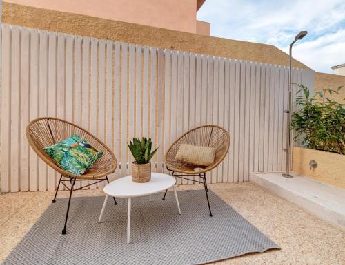 two chairs and a table in front of a wall at Le Palmette Suites in Cagliari