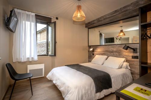 1 dormitorio con cama, silla y espejo en Logis Hôtel restaurant La Remise en Le Bleymard